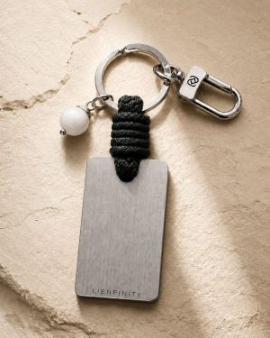 Porte-clé LIENFINITY avec agate blanche, corde noire et plaque gravée sur fond beige texturé