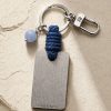 Porte-clé LIENFINITY avec calcédoine bleue, corde bleue et plaque gravée sur fond beige texturé