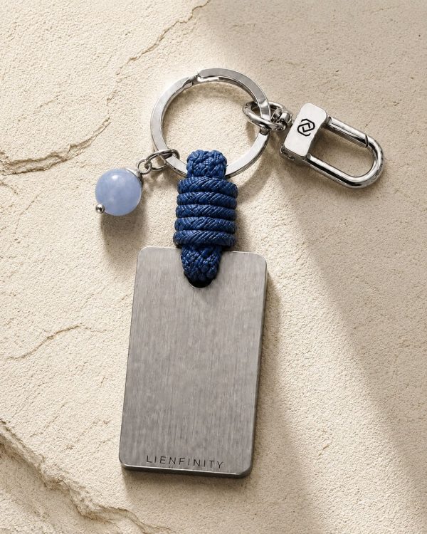 Porte-clé LIENFINITY avec calcédoine bleue, corde bleue et plaque gravée sur fond beige texturé