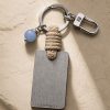 Porte-clé LIENFINITY avec calcédoine bleue, corde sable et plaque gravée sur fond beige texturé