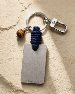 Porte-clé LIENFINITY avec œil de tigre, corde bleue et plaque gravée sur fond beige texturé