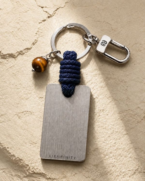 Porte-clé LIENFINITY avec œil de tigre, corde bleue et plaque gravée sur fond beige texturé