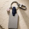 Porte-clé LIENFINITY avec quartz rose, corde bleue et plaque gravée sur fond beige texturé