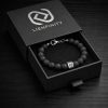 Bracelet LIENFINITY. en Pierre de Lave naturelle noire à texture poreuse, avec insert de connexion en acier inoxydable 316L et Signature QR code. Le bijou est présenté dans son écrin de luxe noir à tiroir avec le logo de la marque argenté.jpg