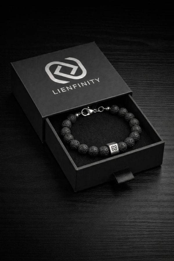 Bracelet LIENFINITY. en Pierre de Lave naturelle noire à texture poreuse, avec insert de connexion en acier inoxydable 316L et Signature QR code. Le bijou est présenté dans son écrin de luxe noir à tiroir avec le logo de la marque argenté.jpg