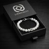 Bracelet LIENFINITY. en pierre naturelle Howlite blanche marbrée de gris , doté d'un insert en acier inoxydable 316L avec Signature QR code. Le bijou est présenté dans son écrin premium noir à tiroir.