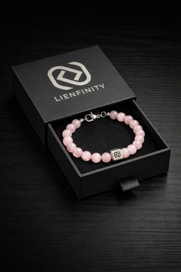 Bracelet LIENFINITY. en pierre naturelle de Quartz Rose translucide avec son insert de connexion en acier inoxydable 316L. Le bijou est présenté dans son écrin de luxe noir à tiroir avec le logo de la marque argenté.