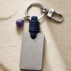 Porte-clé LIENFINITY avec améthyste violette, corde bleue et plaque gravée sur fond beige texturé