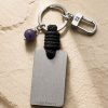 Porte-clé LIENFINITY avec améthyste violette, corde noire et plaque gravée sur fond beige texturé