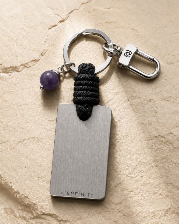 Porte-clé LIENFINITY avec améthyste violette, corde noire et plaque gravée sur fond beige texturé