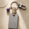 Porte-clé LIENFINITY avec améthyste violette, corde sable et plaque gravée sur fond beige texturé