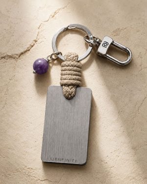 Porte-clé LIENFINITY avec améthyste violette, corde sable et plaque gravée sur fond beige texturé