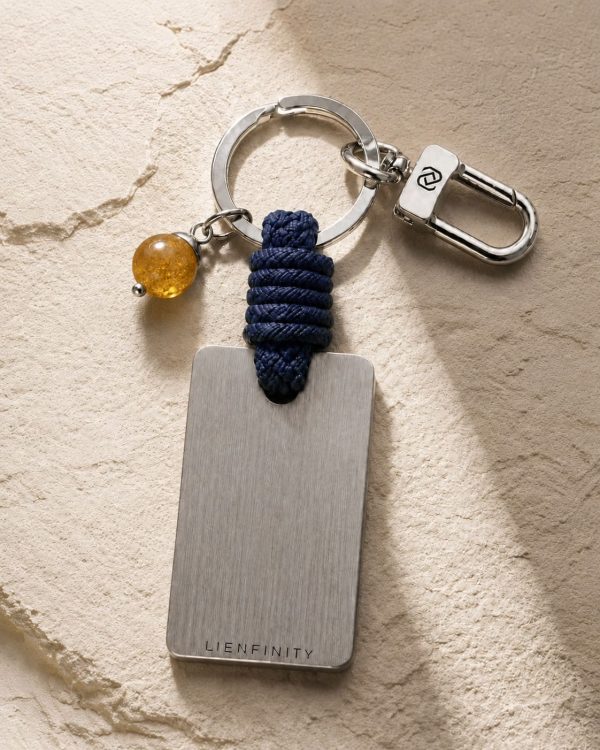 Porte-clé LIENFINITY avec citrine, corde bleue et plaque gravée sur fond beige texturé
