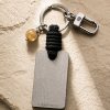 Porte-clé LIENFINITY avec citrine, corde noire et plaque gravée sur fond beige texturé