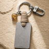 Porte-clé LIENFINITY avec citrine, corde sable et plaque gravée sur fond beige texturé