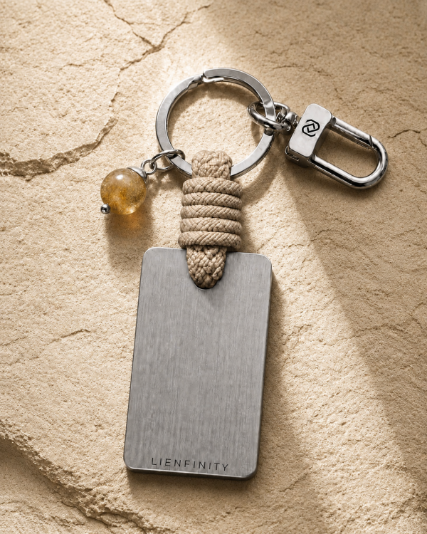 Porte-clé LIENFINITY avec citrine, corde sable et plaque gravée sur fond beige texturé