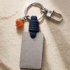 Porte-clé LIENFINITY avec cornaline orange, corde bleue et plaque gravée sur fond beige texturé